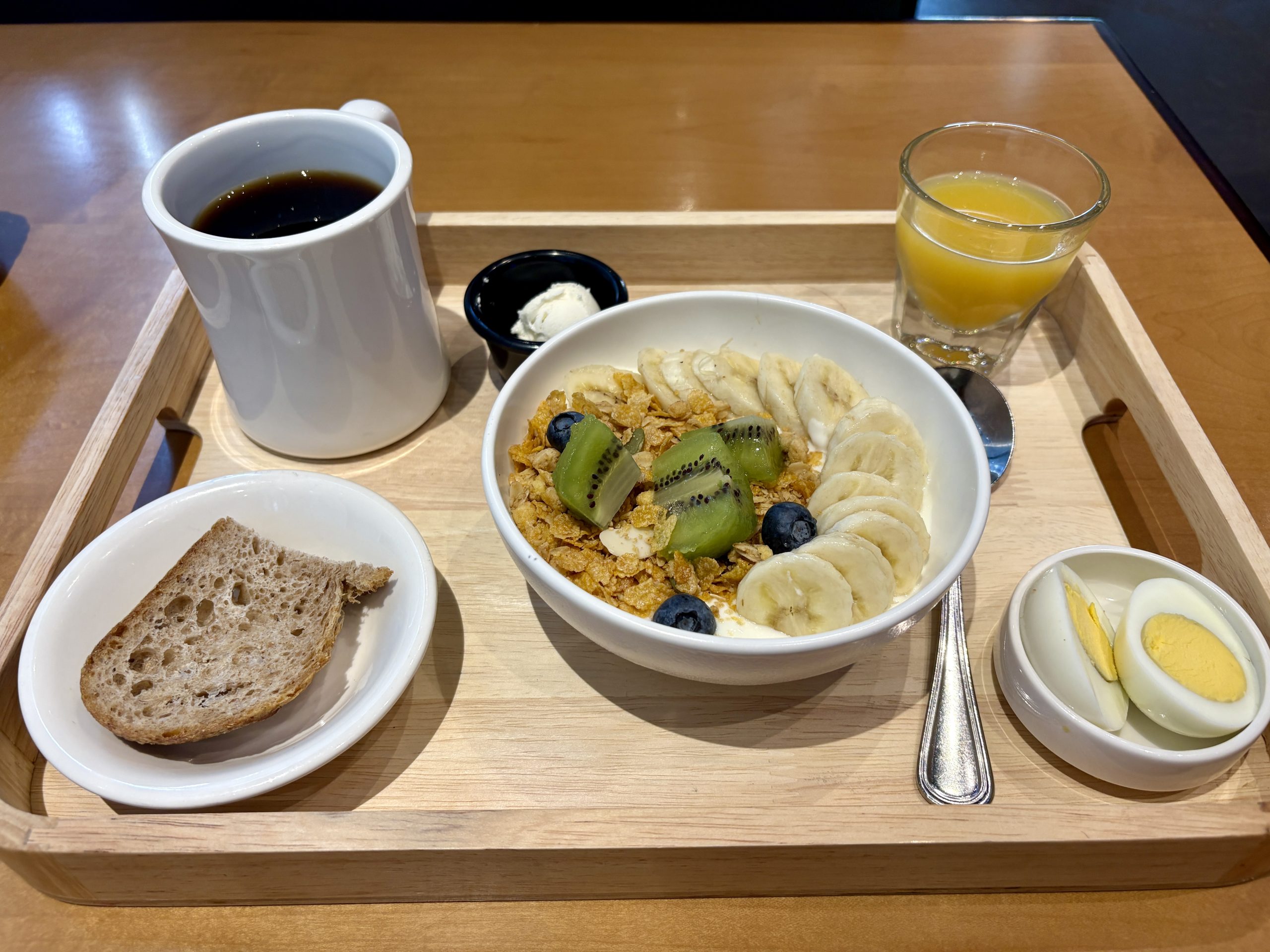 Breakfast set with fruit yogurt bowl, coffee, orange juice, bread, and eggs