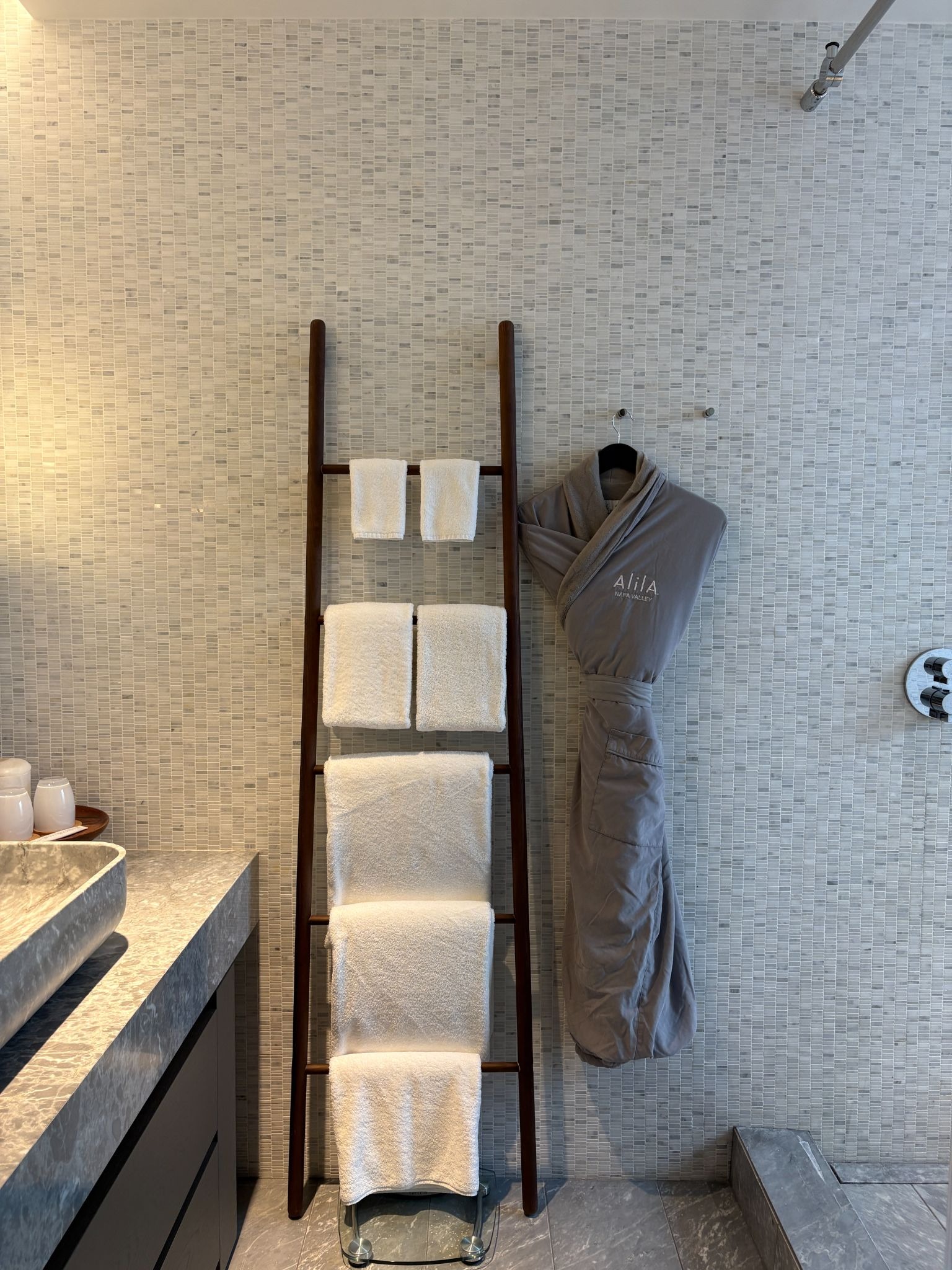 Wooden ladder serving as a towel rack against the bathroom wall