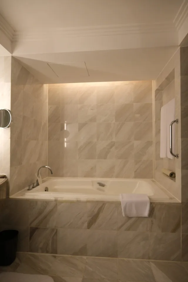 Massive bathtub with marble tiling on one side of the bathroom